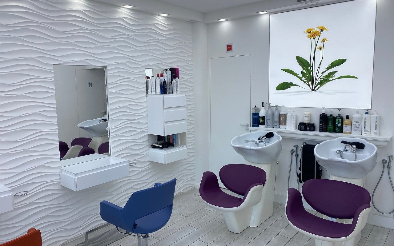 Inside Whistles Hair Salon: purple chairs at the shampoo basins in front of a white wave-textured wall and a dandelion artwork panel