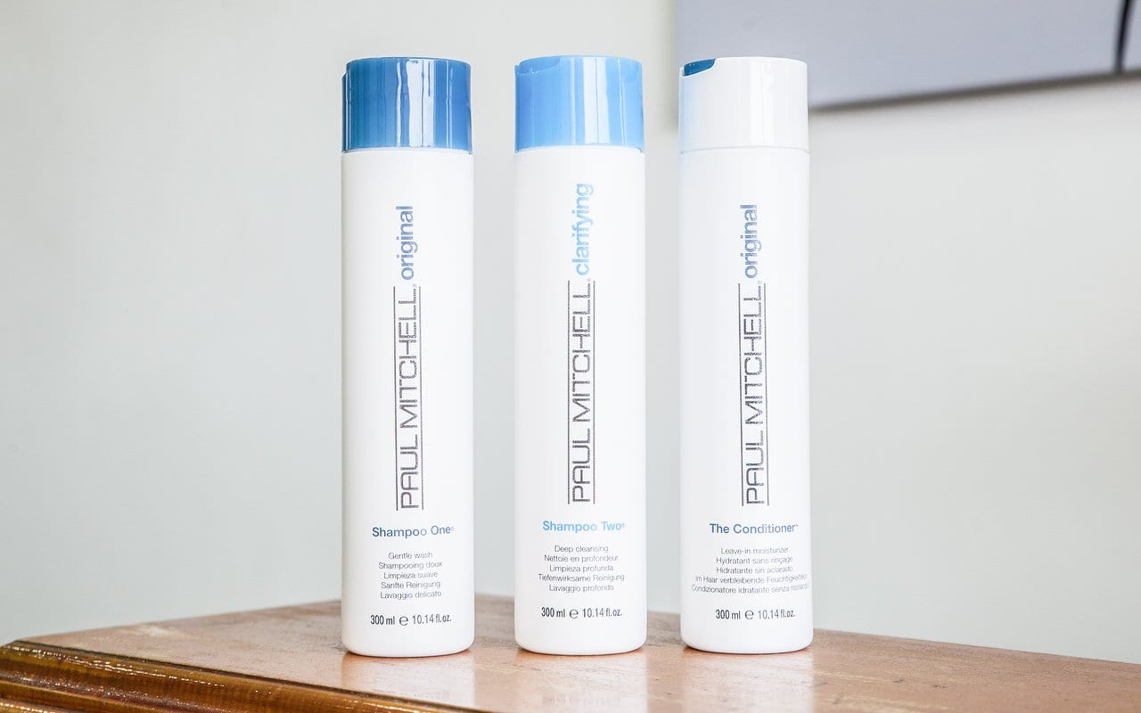 Paul Mitchell Shampoo One, Shampoo Two and The Conditioner bottles on a wooden shelf
