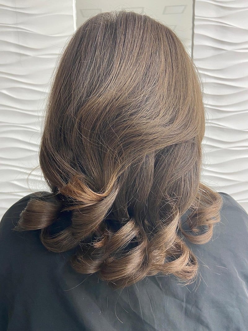 Shoulder-length brown hair with a glossy blow-dry, bouncy curled ends and caramel tips