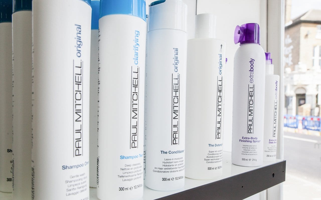 Paul Mitchell shampoos, conditioners and styling sprays lined up on a shelf in the salon window